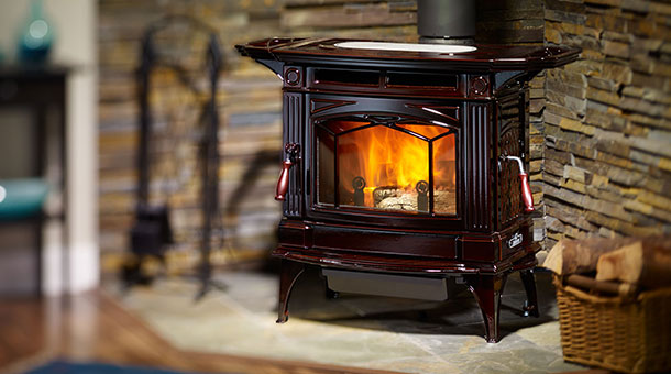 reddish colored stoves with fire burning into it. With brick background and basket of wood in front