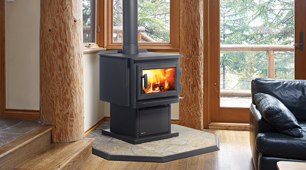 black wood stove with fire burning in room. Black leather couch in front and large windows and glass doors to the right