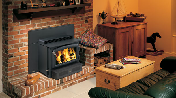 black stove with fire in it and brick hearth background. green couch and table in room
