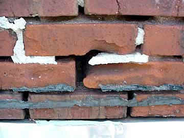 Cracked and broken bricks with caulk around some but missing on others