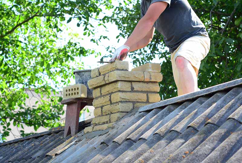 Technician building a chimney on top of a roof